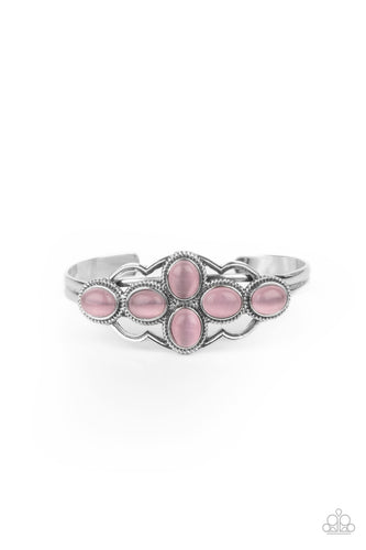 A collection of glowing pink cat's eye stones delicately cluster inside a scalloped silver frame, creating an ethereal centerpiece atop a dainty silver cuff.
