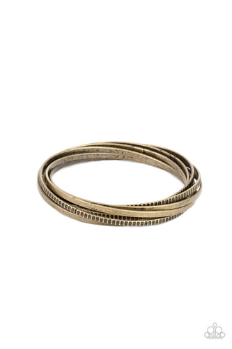 A set of four plain brass bangles interlocks with four brass bangles etched in a tread-like pattern, creating an edgy stacked look around the wrist.