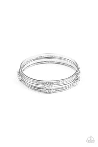 Pairs of plain, textured, and white rhinestone adorned silver bangles glide along the wrist for a sparkly look