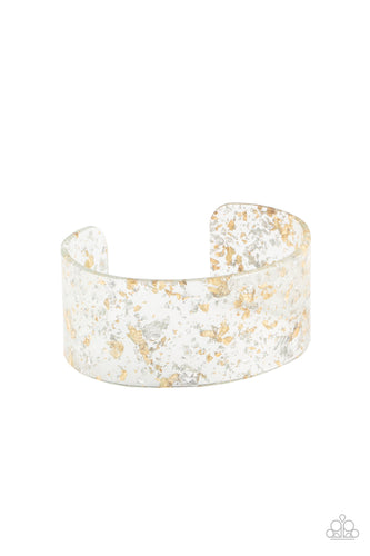 Gold and silver shavings are encased in a thick clear acrylic cuff, creating an icy incandescence around the wrist.