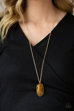 Load image into Gallery viewer, Encased in a classic gold fitting, a glassy Tiger&#39;s Eye stone swings from the bottom of a lengthened gold chain for an elegantly earthy look. Features an adjustable clasp closure.
