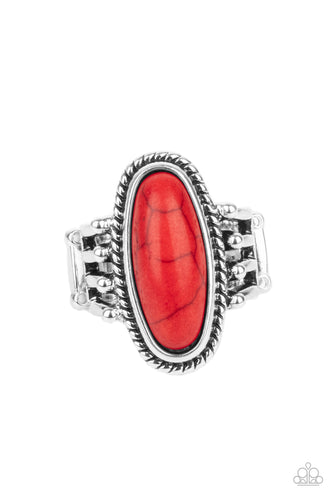 An oblong red stone is pressed into the center of a textured silver frame attached to the studded ends of layered silver bands, creating a colorful rustic centerpiece atop the finger. Features a stretchy band for a flexible fit.