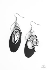 Infused with a glassy white rhinestone, shiny silver ovals, a twisted silver plate, and an oversized black frame trickle along a shimmery silver chain, creating a noise-making tassel. Earring attaches to a standard fishhook fitting. 