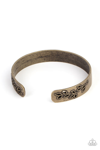 The ends of a dainty brass cuff is cutout and embossed in rustic leafy filigree, creating a simple seasonal centerpiece around the wrist.