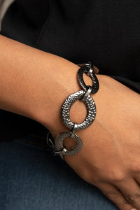 Asymmetrical gunmetal links and hammered oval frames delicately connect around the wrist for an intense industrial look. Features an adjustable clasp closure.