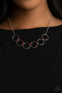 Glittery pink rhinestones link a dainty row of silver rings below the collar, creating a regal minimalist inspired display. Features an adjustable clasp closure.