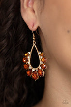 Load image into Gallery viewer, Gradually increasing in size, a glittery collection of topaz teardrop rhinestones fan out from a white rhinestone dotted gold teardrop frame, creating a sparkly statement. Earring attaches to a standard fishhook fitting.
