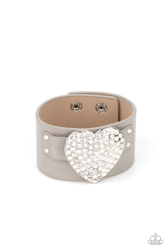 Encrusted in blinding white rhinestones, an oversized silver heart frame is studded in place across the front of a gray leather band, creating a flirtatious centerpiece around the wrist. Features an adjustable snap closure. 