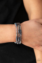 Load image into Gallery viewer, Infused with faceted silver beads, a glamorous collection of metallic blue crystals and smoky beads are threaded along stretchy bands around the wrist, creating glittery layers. 
