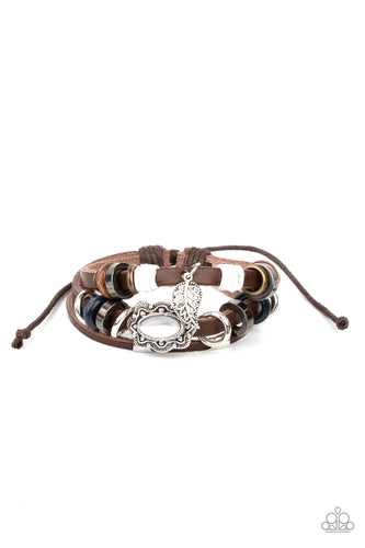 Infused with a scalloped white cat's eye stone centerpiece, three layered leather bands are embellished with a mismatched collection of wooden and metallic rings for a seasonal finish. Features an adjustable sliding knot closure.
