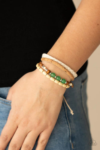 Featuring cork, thread, and wood, mismatched metallic accents, glassy jade stones, and wood beads adorn earthy layers around the wrist for a whimsical look. Features an adjustable sliding knot closure.