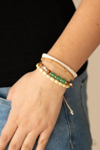 Featuring cork, thread, and wood, mismatched metallic accents, glassy jade stones, and wood beads adorn earthy layers around the wrist for a whimsical look. Features an adjustable sliding knot closure.