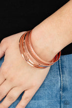 Load image into Gallery viewer, Varying in hammered, textured, and high sheen finishes, a mismatched collection of shiny copper bangles stacks across the wrist for a classic fashion. 
