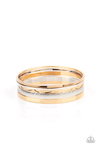 Varying in hammered, textured, and high sheen finishes, a mismatched collection of gold and silver bangles stacks across the wrist for a classic fashion.