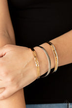 Load image into Gallery viewer, Varying in hammered, textured, and high sheen finishes, a mismatched collection of gold and silver bangles stacks across the wrist for a classic fashion.
