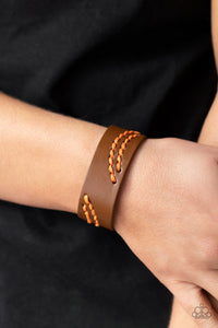 Marigold cording is stitched across the front of a brown leather band, creating curved patterns. Features an adjustable snap closure. 