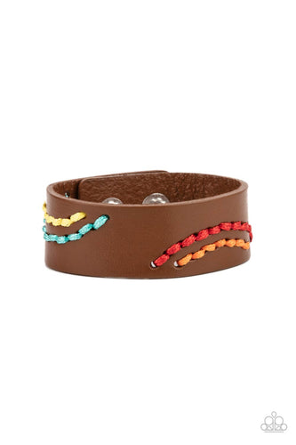 Multicolored cording is stitched across the front of a brown leather band, creating curved patterns. Features an adjustable snap closure.
