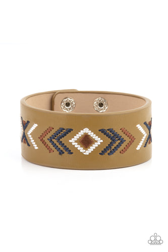 Blue, brown, and white thread is stitched across the front of a Willow leather band, creating a colorful tribal inspired pattern. Features an adjustable snap closure.