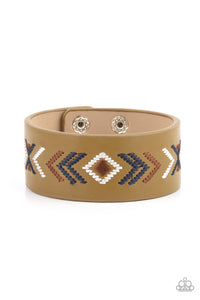 Blue, brown, and white thread is stitched across the front of a Willow leather band, creating a colorful tribal inspired pattern. Features an adjustable snap closure.