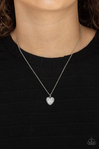 A lovely silver heart frame, encrusted with tiny glittery silver blocks creates a fun 3D pendant that falls below the collar from a dainty silver chain. Features an adjustable clasp closure. 