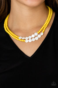 A summery collection of shiny white shell-like discs and dainty yellow beads are threaded along invisible wires, creating colorful layers falling below the collar. Features an adjustable clasp closure.