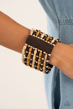 Load image into Gallery viewer, Held together with rectangular wooden frames, an earthy collection of white wooden beads and black, brown, and tan oval wooden beads are threaded along stretchy bands around the wrist for a bold beach inspired fashion.
