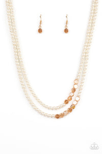 A posh collection of pearly white beads, accented with sections of flat, faceted shimmery transparent gold beads, is threaded along invisible wires, creating sophisticated layers that fall below the collar. Features an adjustable clasp closure.