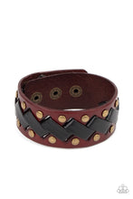 Load image into Gallery viewer, Thick black leather laces zigzag across the front brass studded brown leather band, creating a rustic display around the wrist. Features an adjustable snap closure.
