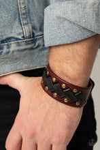 Load image into Gallery viewer, Thick black leather laces zigzag across the front brass studded brown leather band, creating a rustic display around the wrist. Features an adjustable snap closure.
