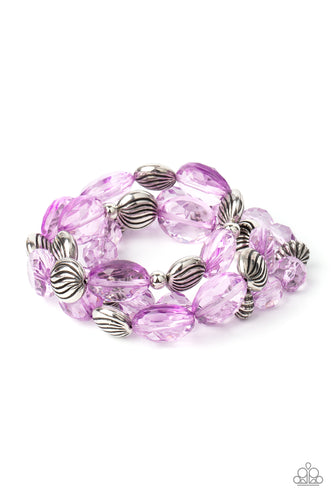 A mismatched collection of sparkly purple crystal-like beads and textured silver accents are threaded along stretchy bands around the wrist, creating glamorous layers.