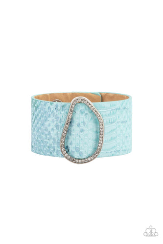 Encrusted with glassy white rhinestones, an asymmetrical silver fitting glides along a blue leather band adorned in a metallic python print for a wild look. Features an adjustable snap closure.