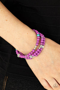 A collection of purple and turquoise stone beads, silver cube beads, and ornate silver accents are threaded along invisible bands around the wrist, creating vivacious layers. Features an adjustable clasp closure 