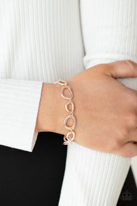 An array of irregular shaped rose gold rings link together and make their way around the wrist for a simple yet stylish avant-garde fashion. Features an adjustable clasp closure.