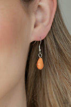 Load image into Gallery viewer, A silver feather, palm leaf, and dainty silver flower overlap atop an oversized orange stone teardrop that is nestled inside a textured scalloped frame, creating a dramatic pop of color at the bottom of a lengthened silver chain. Features an adjustable clasp closure. 

