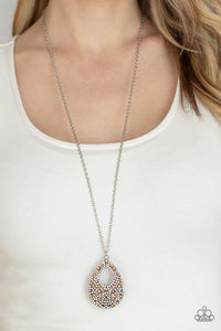 A sparkly explosion of glassy white and golden topaz rhinestones haphazardly coalesce into a teardrop frame at the bottom of a lengthened silver chain, creating a twinkly pendant. Features an adjustable clasp closure.