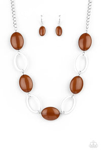 Shiny silver ovals and glassy brown oval beads delicately link across the chest, creating a whimsical pop of color. Features an adjustable clasp closure.