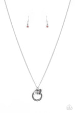 Load image into Gallery viewer, Dotted with a sparkly pink rhinestone, a dainty silver heart joins a silver ring stamped in the biblical passage, &quot;Trust in the Lord with all thine heart,&quot; and a silver disc stamped in, &quot;Proverbs 3:5,&quot; along the bottom of a lengthened silver chain, creating an inspirational pendant. Features an adjustable clasp closure.
