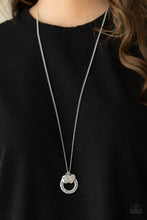 Load image into Gallery viewer, Dotted with a sparkly pink rhinestone, a dainty silver heart joins a silver ring stamped in the biblical passage, &quot;Trust in the Lord with all thine heart,&quot; and a silver disc stamped in, &quot;Proverbs 3:5,&quot; along the bottom of a lengthened silver chain, creating an inspirational pendant. Features an adjustable clasp closure.
