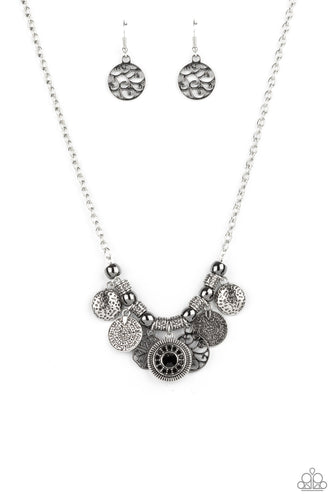 A collection of silver coin-like discs, gunmetal vine-like frames, and hammered silver frames alternate with silver beads and ornate silver accents along the bottom of a classic silver chain. Dotted with glassy black rhinestones, a glittery frame adorns the center of the mismatched frames, adding a hint of sparkle to the rustic fringe. Features an adjustable clasp closure.