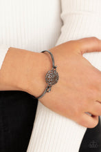 Load image into Gallery viewer, Shiny gunmetal filigree swirls into a round frame that hooks to a dainty gunmetal bangle-like cuff, creating a whimsical centerpiece. Features a hinge-like closure.
