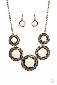 Earthy white stones, pressed into round antiqued brass frames featuring dot and interlinking loop motifs, create a dramatically rustic statement as they link across the collar. Features an adjustable clasp closure.