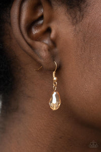 An oversized scalloped teardrop frame, tipped on its point, encases rows of sparkling white rhinestones in its lustrous gold fittings. Shimmery faceted champagne teardrop beads dangle daintily from the scalloped frame for an exquisitely eye-catching pendant at the end of a lengthened gold chain.  Features an adjustable clasp closure. 