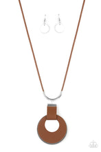 Load image into Gallery viewer, A large cutout silver disc, overlaid with brown leather, is cradled in a wide brown leather strap. The luxe pendant sways from a U-shaped silver cylinder threaded along the end of a lengthened polished brown cord for an indulgently lavish finish. Features a sliding bead closure. 
