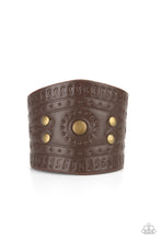 Load image into Gallery viewer, Dotted in rustic brass studs, a triangular piece of brown leather is stamped in indigenous inspired patterns for an urban flair. Features an adjustable snap closure.
