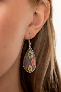Dainty green, pink, purple, and yellow flowers are encased in a glassy teardrop, creating a whimsical frame. Earring attaches to a standard fishhook fitting.