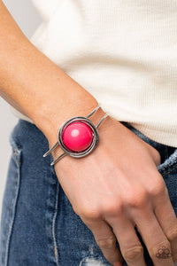 An oversized Raspberry Sorbet bead is pressed into the center of overlapping silver rings that coalesce into a dizzying centerpiece atop an airy silver bangle-like cuff, creating a bold pop of color atop the wrist. Features a hinged closure.