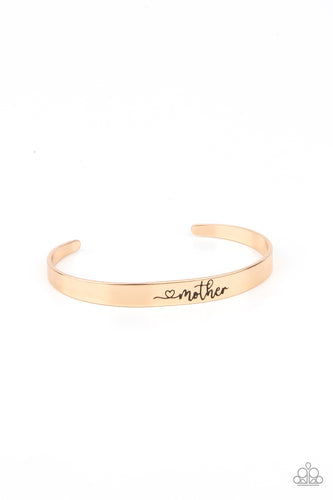 A dainty gold cuff is stamped in a heart and the word, 