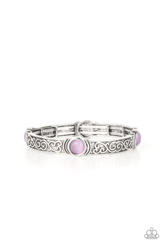 A purple cat's eye stone is pressed into a round frame at the end of a silver bar. Embossed with a whimsical vine motif, the patterned bars are threaded on stretchy bands to repeat around the wrist for an enchanting finish.