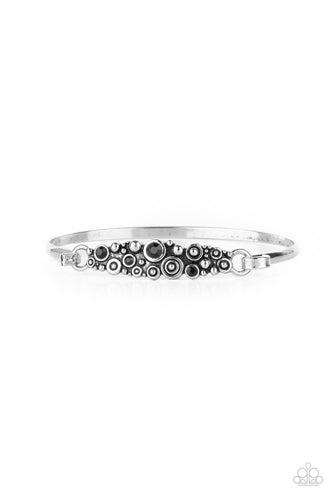 A cluster of engraved and antiqued silver swirls merge with jet black beads and coalesce into a whimsical display across the wrist on a dainty silver cuff. Features a hook and eye closure. 