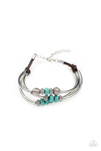 Load image into Gallery viewer, A mismatched collection of ornate silver accents, turquoise stone beads, and cylindrical silver bars are threaded along three rows of leathery brown cording, creating whimsical layers around the wrist. Features an adjustable clasp closure.
